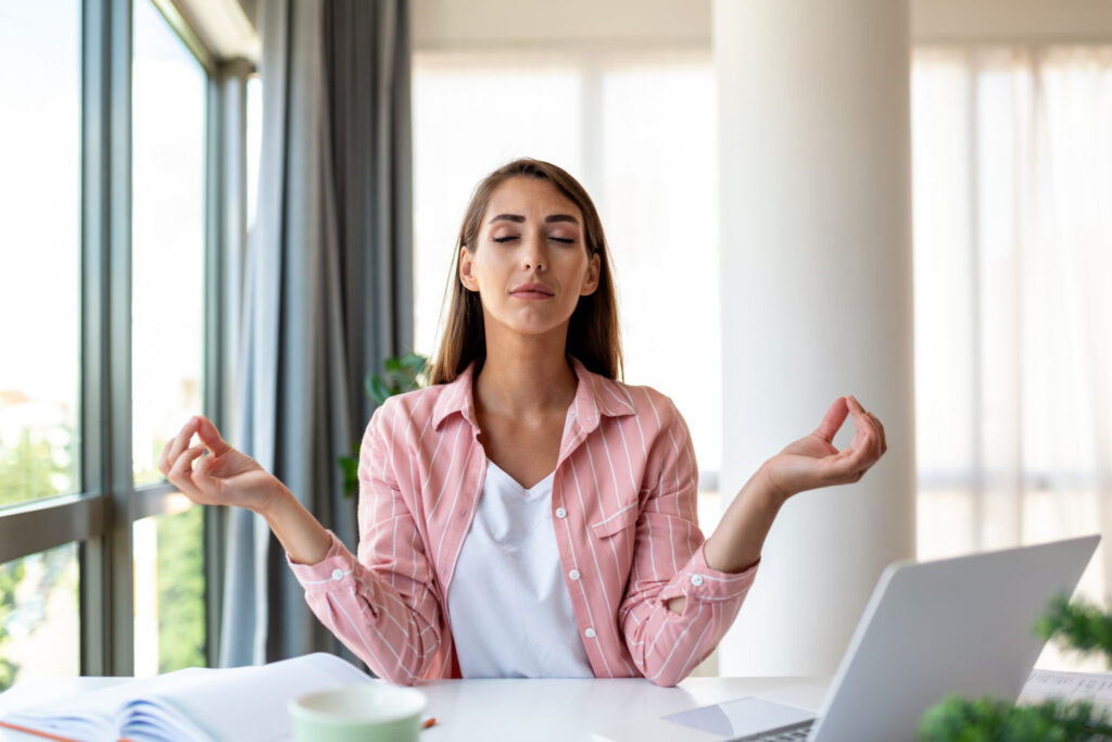 atelier manuel antistress - Calm woman relaxing meditating with laptop, no stress free relief at work concept, mindful peaceful young businesswoman or student practicing breathing yoga exercises at workplace, office meditation